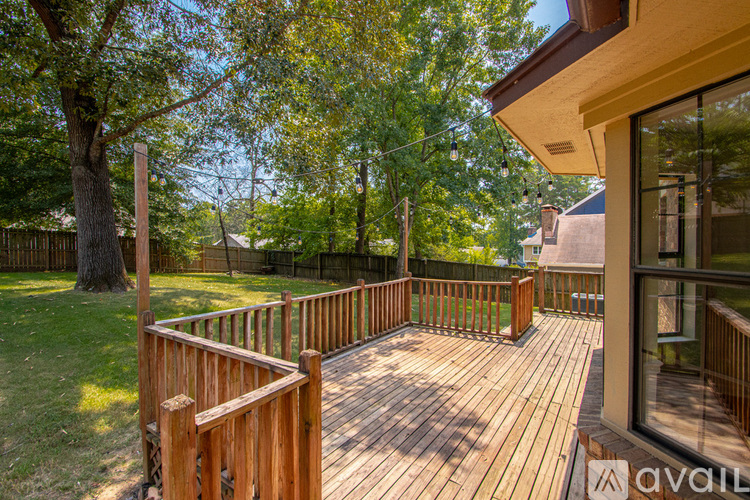 A wooden deck with a railing and a tree in the background.