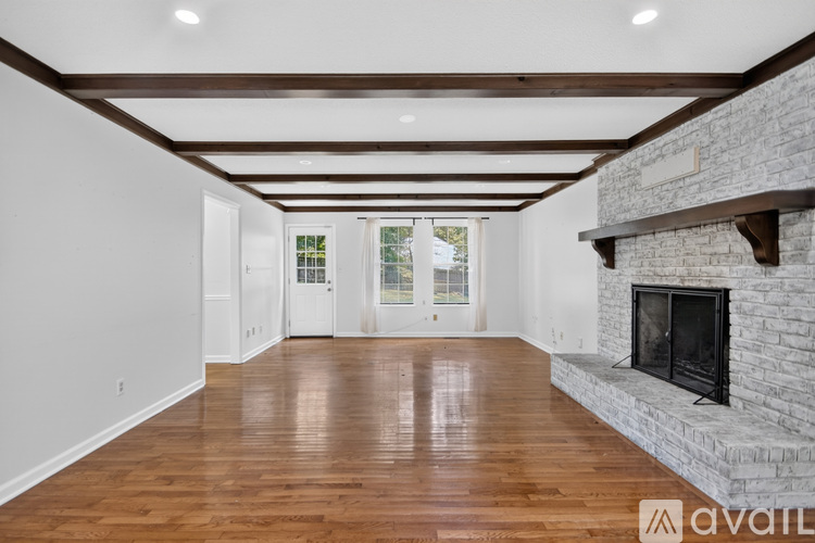 A spacious room with wooden floors and a stone fireplace.