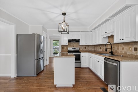 A kitchen with white cabinets and a wooden floor.