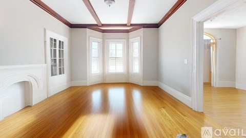A spacious room with wooden floors and white walls.