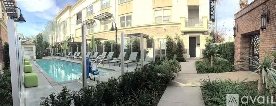 A pool area with lounge chairs and a building in the background.