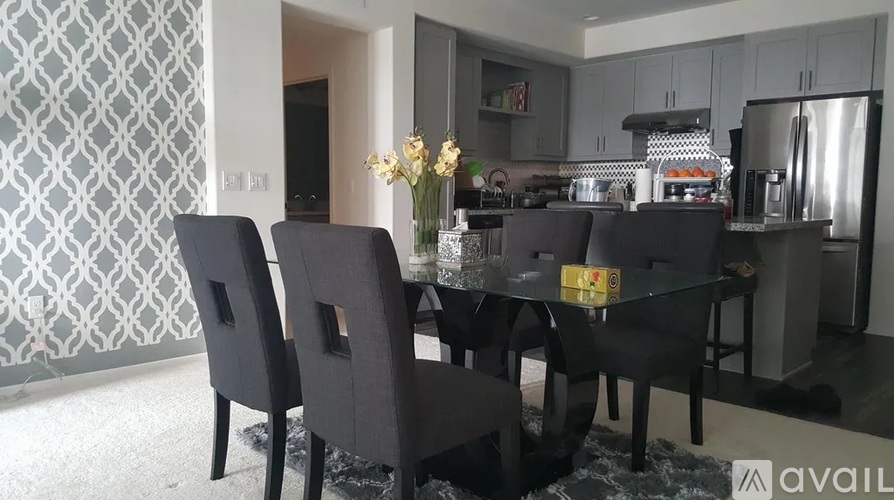 A modern kitchen with a glass table and black chairs.