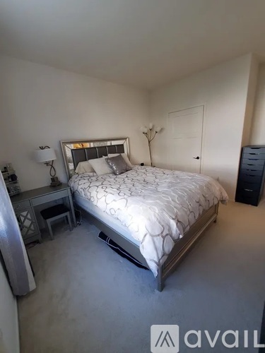 A bedroom with a large bed, a nightstand, and a dresser.