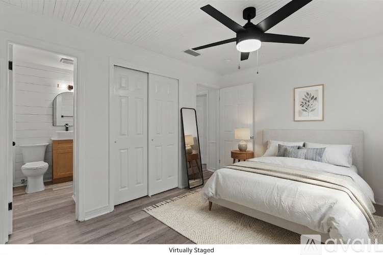 A bedroom with a bed, dresser, mirror, and a toilet in the bathroom.