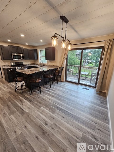 A modern kitchen with wooden flooring and a bar area.