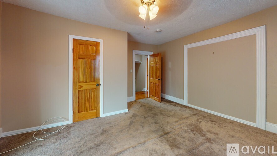 A room with a carpeted floor and a chandelier hanging from the ceiling.