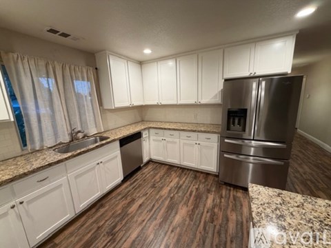 A kitchen with white cabinets and a granite countertop.