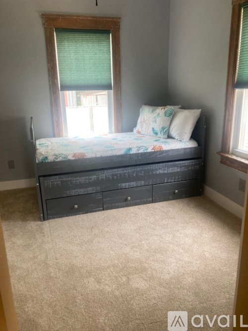 A bedroom with a bed, dresser, and carpeted floor.