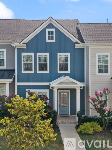 A blue house with a front porch and a green bush to the left.