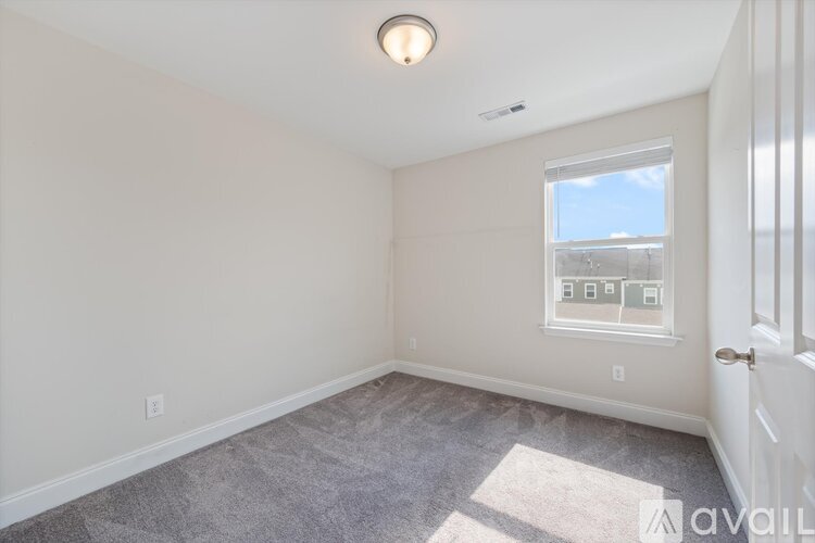 A room with a window showing a view of a building and a door on the right side.