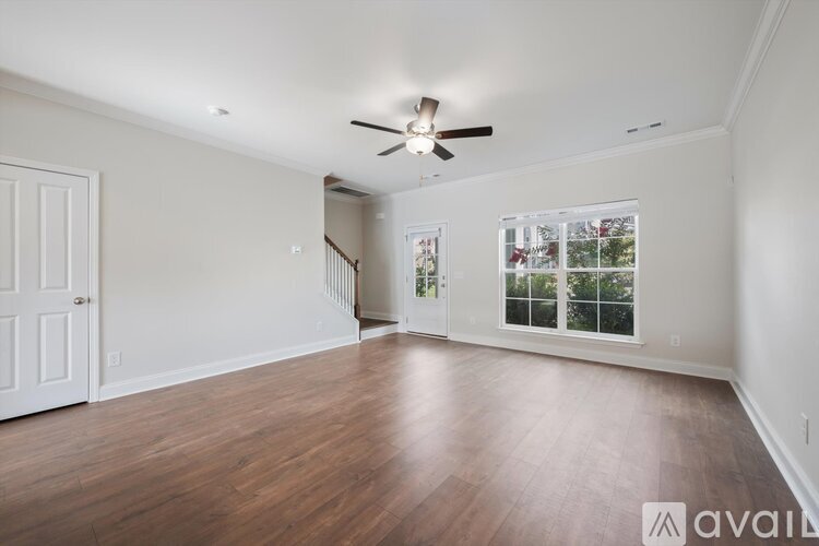 A spacious room with a ceiling fan and wooden flooring.