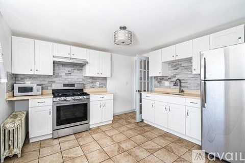 A kitchen with white cabinets and a stone backsplash.