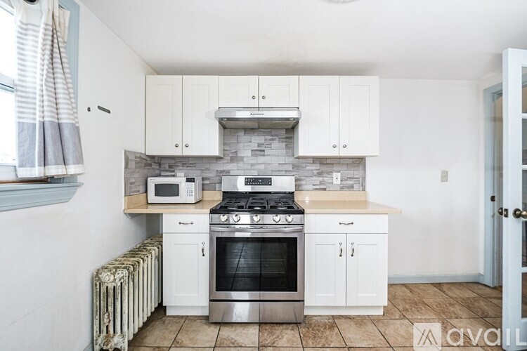 A kitchen with white cabinets and a stove top oven.