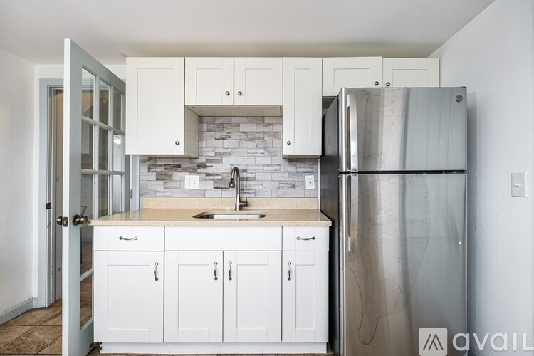 A kitchen with white cabinets and a stainless steel refrigerator.