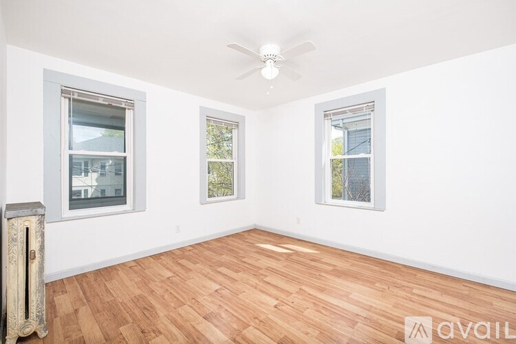 A room with wooden flooring and two windows.
