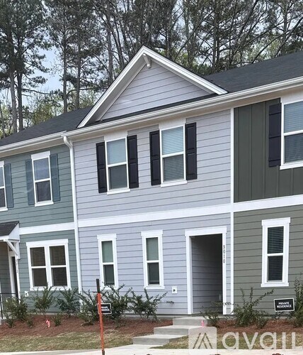 A house with a grey and white exterior is seen from the front of a car.