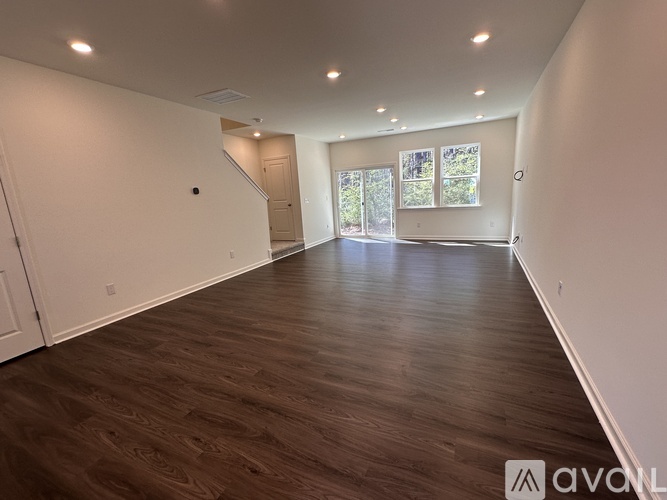 A spacious room with wooden flooring and white walls.