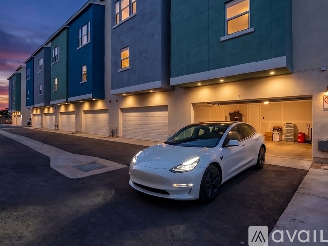 A white Tesla car is parked in front of a building.