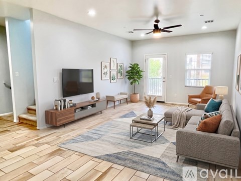 A living room with a grey couch, a wooden floor, and a television on the wall.