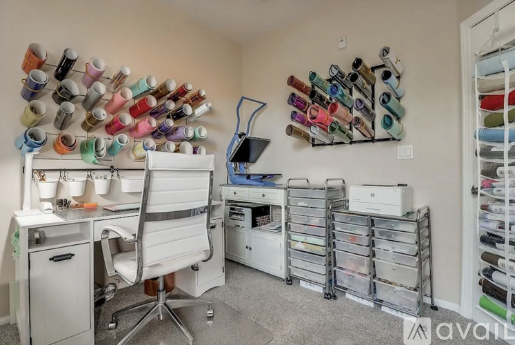 A room with a white chair, a desk, and a wall of spools of thread.