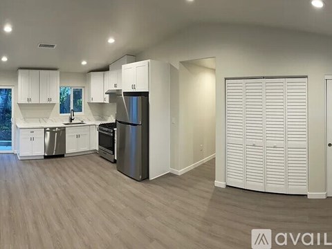 A modern kitchen with white cabinets and a wooden floor.