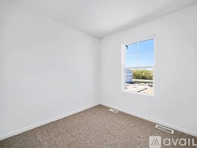 A room with a window showing a view of a parking lot and trees.