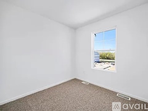A room with a window showing a view of a parking lot and trees.