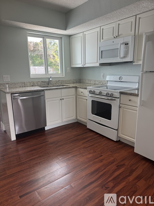 A kitchen with white appliances and wooden floors.