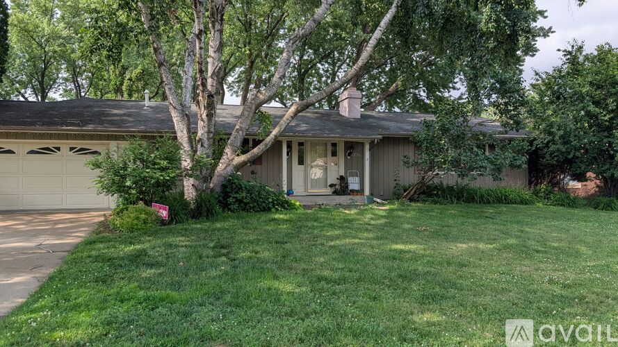 A house with a garage and a tree in front of it.