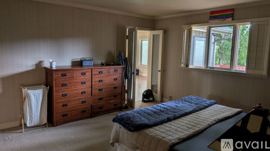 A bedroom with a bed, dresser, and window.