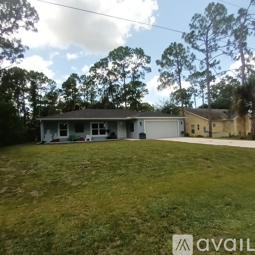 A house with a garage is surrounded by trees and grass.