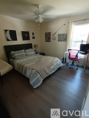 A bedroom with a bed, chair, and pictures on the wall.