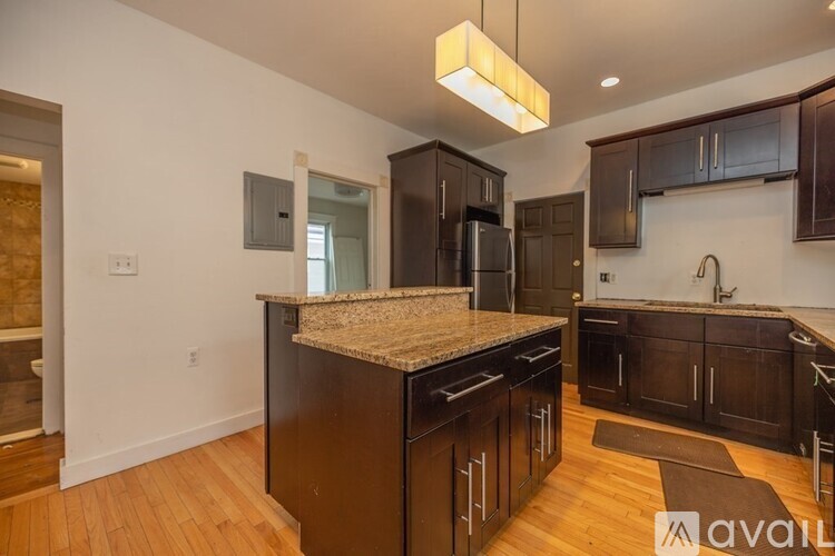A kitchen with dark wood cabinets and a granite countertop.