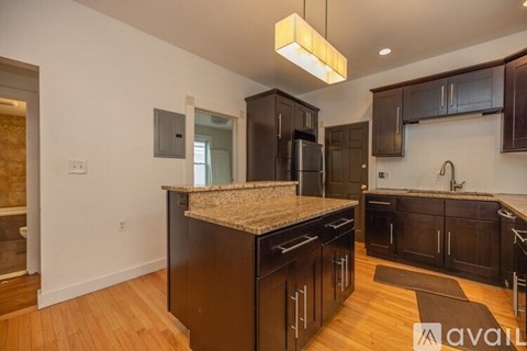 A kitchen with dark wood cabinets and a granite countertop.
