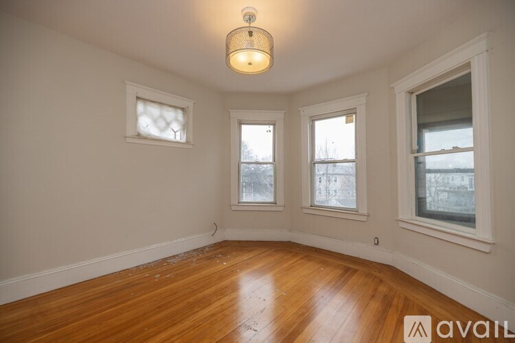 A room with wooden floors and three windows.