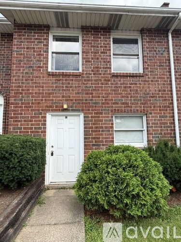 A red brick house with a white door and two windows.