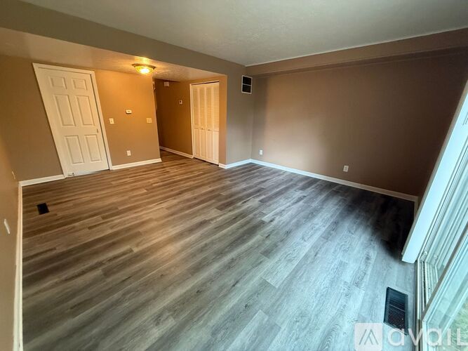 A room with wooden flooring and two doors.