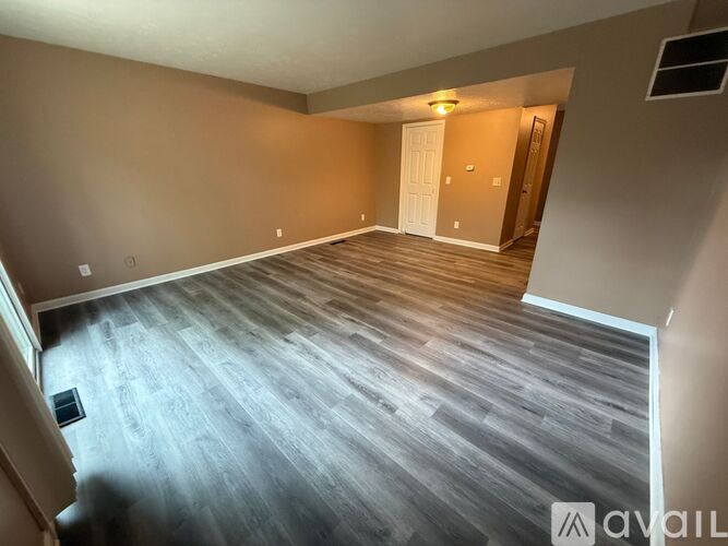 A spacious room with wooden flooring and a white door.