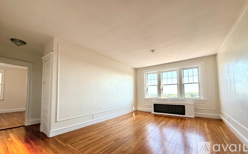 A room with wooden floors and white walls, with a window and a radiator.