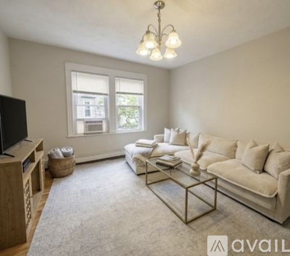 A living room with a white couch and a glass coffee table.