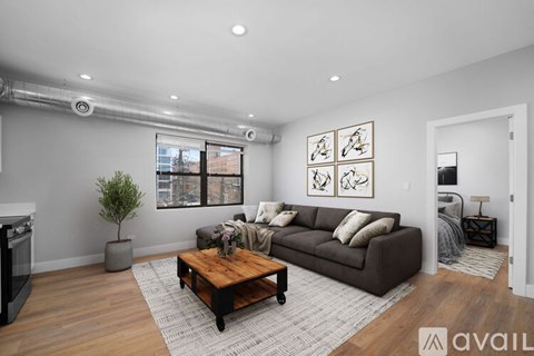 A living room with a brown couch, a coffee table, and a plant.