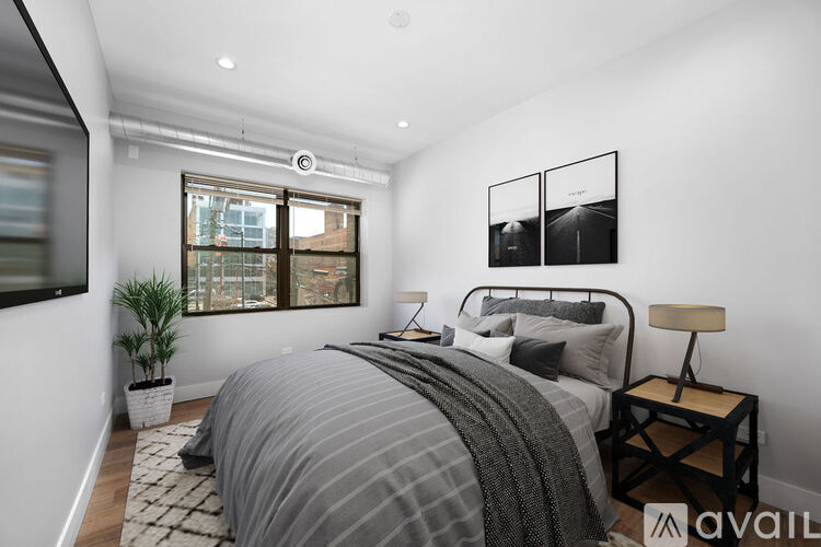 A bedroom with a large bed and a window overlooking a cityscape.
