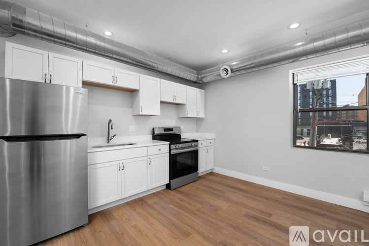 A kitchen with white cabinets and a stainless steel refrigerator.