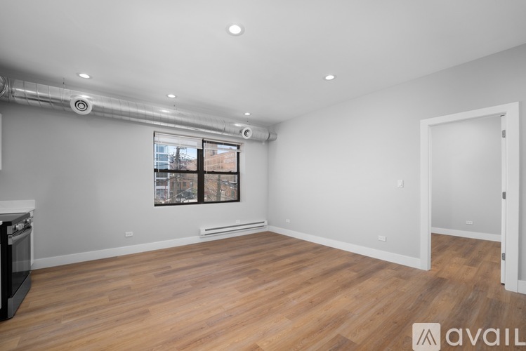 A spacious room with wooden flooring and a window with a view of a cityscape.