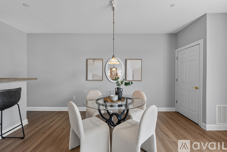 A dining room with a glass table and white chairs.