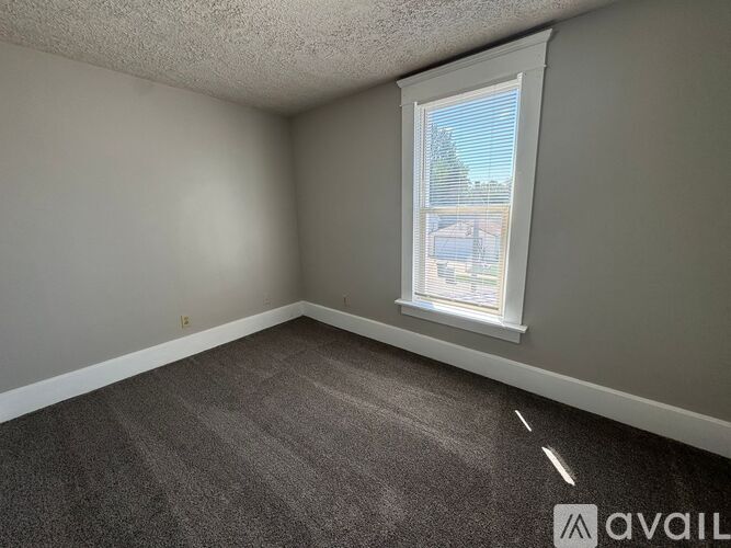 A room with a carpeted floor and a window showing a view of a building outside.