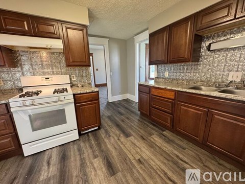 A kitchen with a white stove top oven and wooden cabinets.