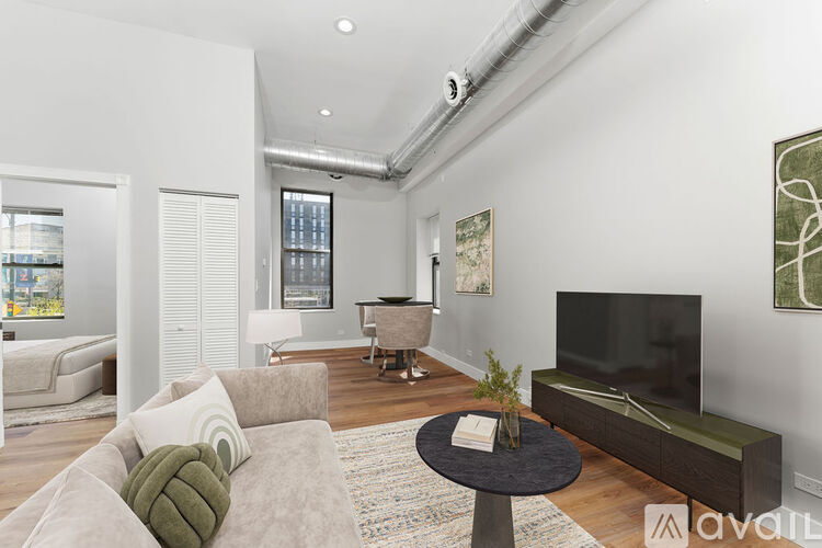 A living room with a grey couch, a black coffee table, and a large flat screen TV.