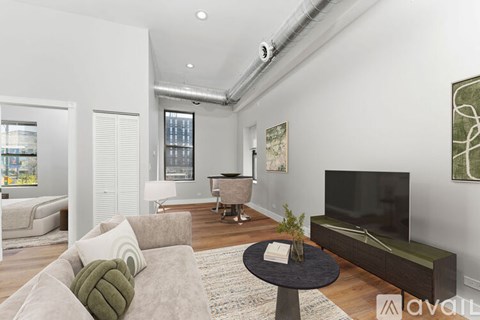 A living room with a grey couch, a black coffee table, and a large flat screen TV.