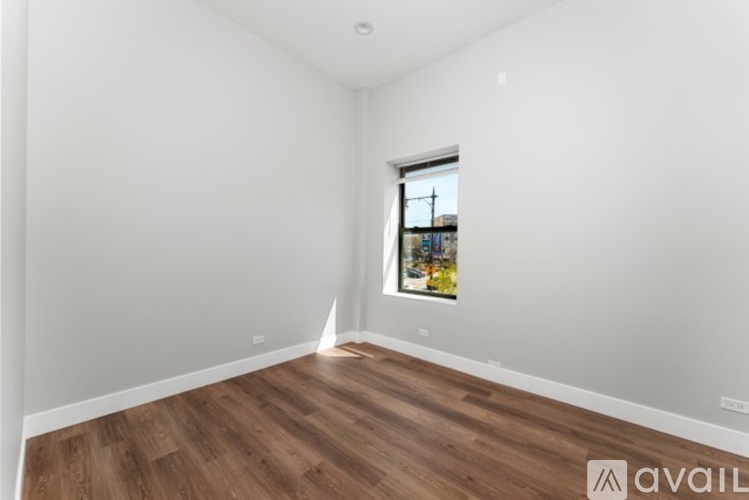 A room with wooden flooring and a window showing a view of buildings outside.